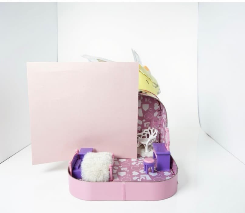 Suitcase being styled, with a blush-pink card held up behind the open lid to test how the colour palette reads.