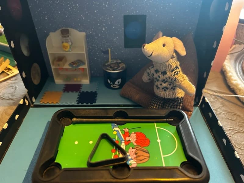 Miniature games room scene in a suitcase with pool table and bar.